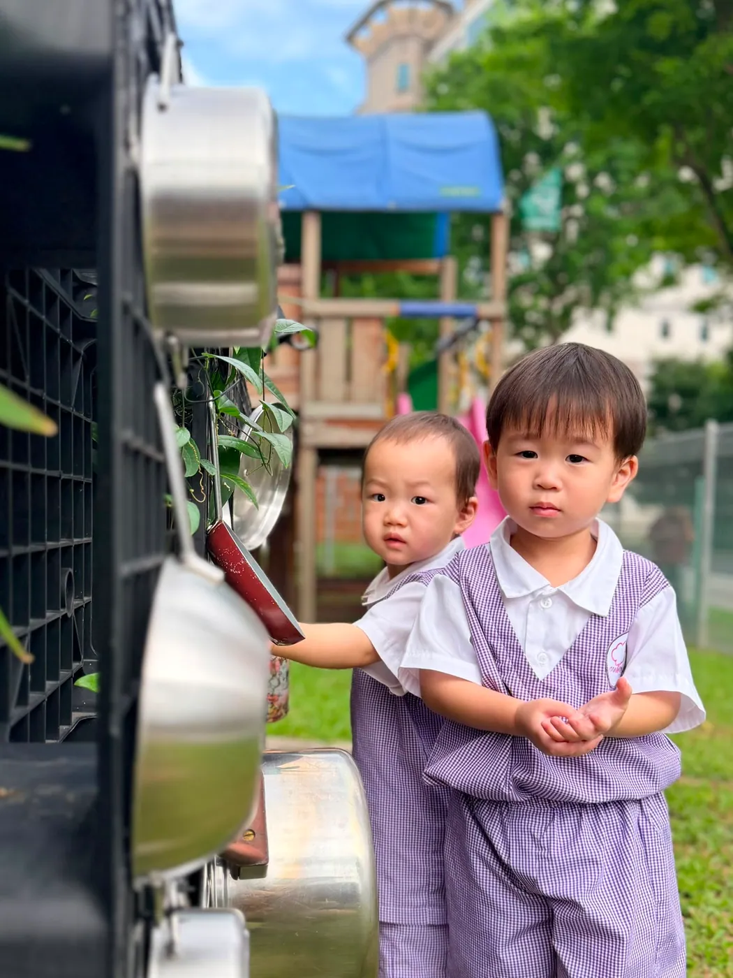 Children exploring the outdoor mud kitchen beside the playground structure