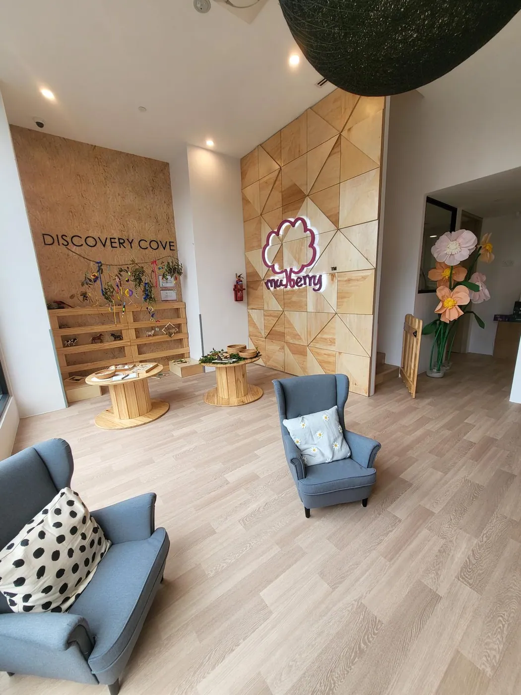 A warm reception lounge with the Mulberry logo and giant paper flowers
